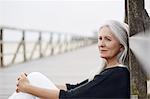 Pensive senior woman relaxing on beach boardwalk