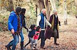 Multi-generation family holding hands walking in autumn park