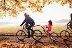 Father and daughter bike riding with trailer bike in sunny autumn park