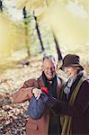 Grandparents using cell phone in autumn park