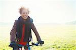 Smiling woman bike riding in sunny park grass