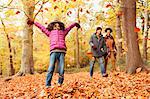 Playful girl throwing autumn leaves in woods