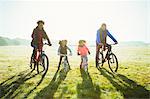 Portrait young family bike riding in sunny autumn park grass