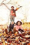 Playful mother and daughters throwing autumn leaves in sunny park