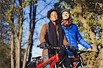 Smiling couple with bicycles in sunny autumn park