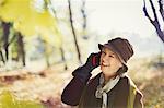 Senior woman talking on cell phone in sunny autumn park