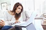 Serious woman using laptop at dining table