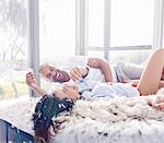 Feathers around playful couple pillow fighting in bedroom