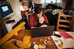 A woman seated with her baby on her lap, multitasking and using a laptop.