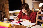 A woman seated at a table making notes, writing in a notebook.