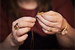 A woman using a needle threaded with cotton thread.