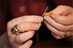 A woman using a needle threaded with cotton thread.