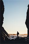 Silhouette of man standing between tall cliffs at dusk, the Pacific Ocean in the distance, Olympic National Park, Washington, USA.