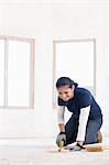 A female builder measuring a plank of wood