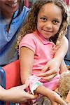 Nurse putting bandage on girls arm