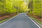 Driving along paved road through the spring forest at Amorbach in Odenwald, in Lower Franconia, Bavaria, Germany