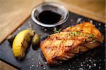 Grilled Scottish salmon with soy sauce and herb by lemon served on a stone board