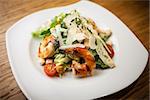 Caesar Salad with shrimps served on a plate in restaurant