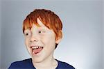 Studio portrait of smiling red haired boy looking sideways