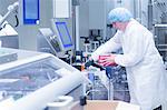 Worker retrieving packaged products from production line in pharmaceutical plant