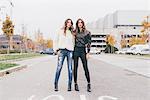 Portrait of twin sisters, in urban area, standing side by side