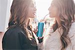 Twin sisters, outdoors, drinking can of soft drink with straws