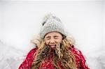 Girl lying on back in snow with eyes closed