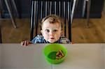 Portrait of blue eyed male toddler looking up from table