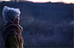 Portrait of mature grey haired woman gazing at dusk landscape