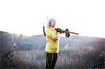 Mature woman carrying pick axe over her shoulder in landscape