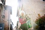 Woman in street looking at smartphone smiling. Bruniquel, France