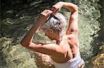 Woman in water wearing swimsuit tying hair