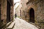 Woman walking in narrow rural street, Bruniquel, France