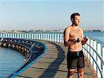 Swimmer holding swimming goggles on boardwalk, Eastern Beach, Geelong, Victoria, Australia