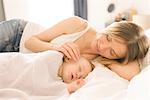 Mother watching over sleeping baby on bed