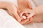 Mother holding baby's hands on bed