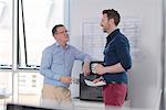 Male colleagues talking by photocopier machine