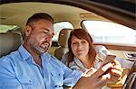 Couple in car, looking at smartphone