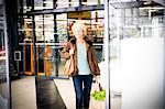 Mature woman exiting supermarket with bag of shopping