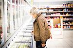 Mature woman in supermarket, looking in freezer cabinet