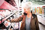 Mature woman in supermarket, looking at chilled meat section