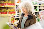 Mature woman in supermarket, reading back of packaging