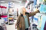 Mature woman in supermarket, looking at homeware section