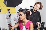 Hairdresser styling model's long hair in photography studio