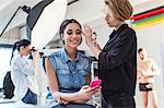 Make up artist applying eye shadow to model in photography studio