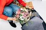 Neck down view of female florist wrapping flower bouquet in florists workshop