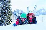 Portrait of skiing teenage girl and brother lying in snow, Gstaad, Switzerland