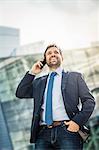 Happy businessman making smartphone call in city