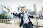 Happy businessman holding out digital tablet on city waterfront