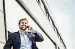 Businessman making smartphone call outside office building